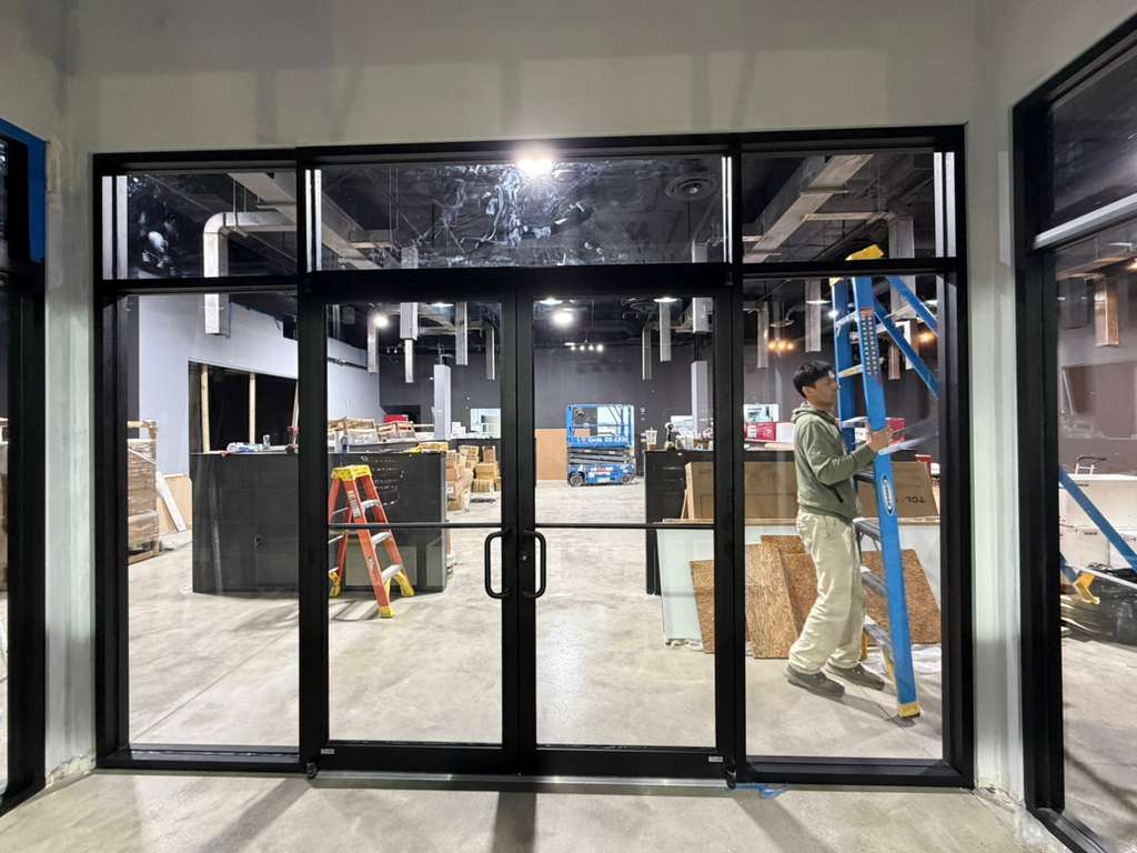 Installer fitting a storefront glass door on site