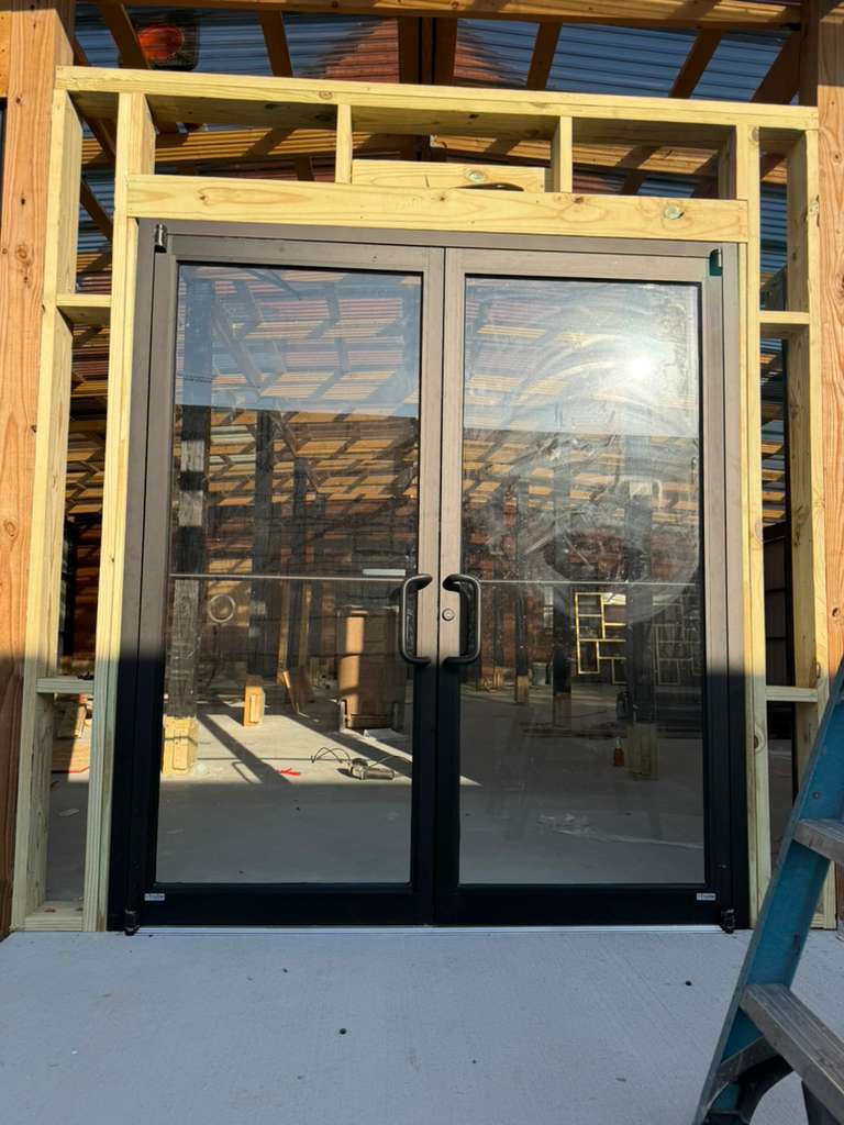Bronze-frame storefront double door in a wood-framed opening