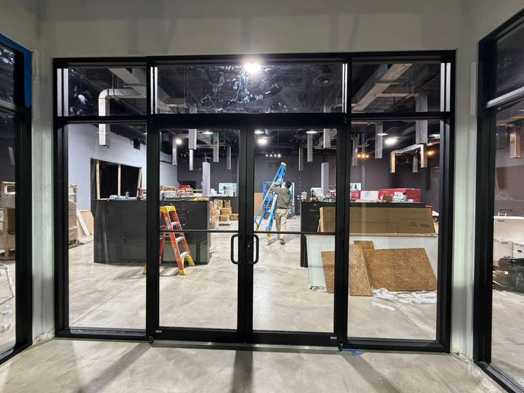 Storefront glass door installation with crew member on site