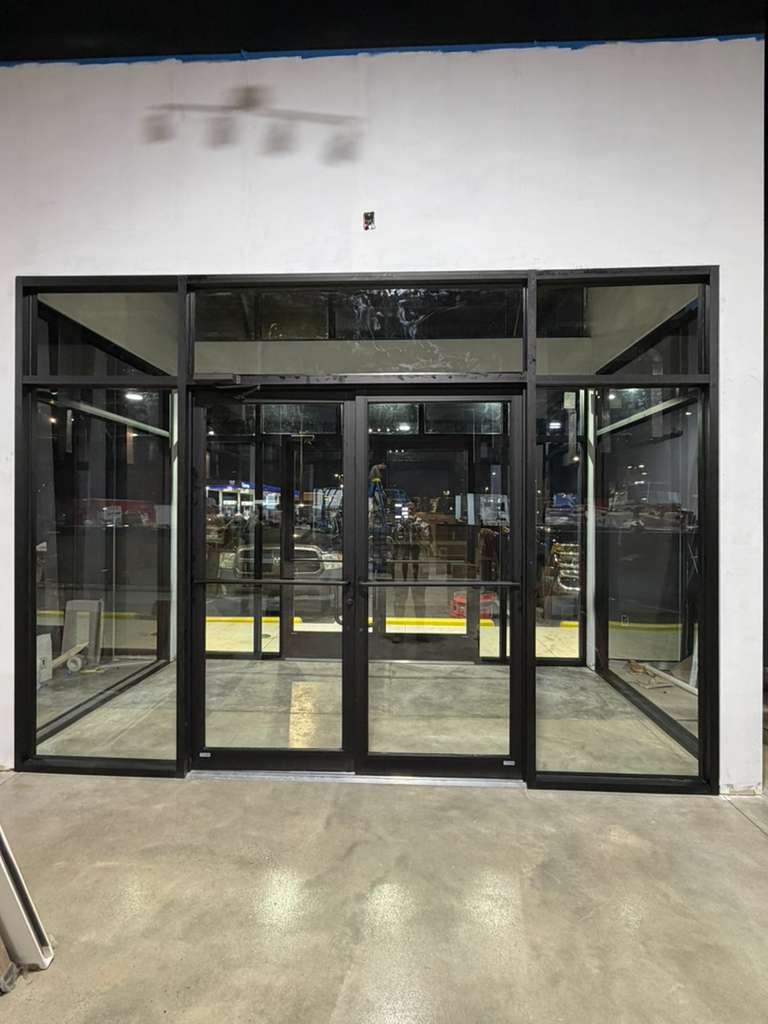 Completed storefront entrance with black aluminum framing and canopy lighting
